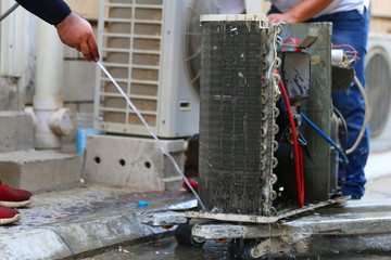 Worker to cleaning coil cooler of air conditioner by water for clean a dust on the wall in customer home when maintenance service