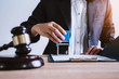 © ordinary042 - Business woman sitting with brass scale at lawyer desk, Lawyer working hand holding automatic stamp important documents in office. lawyer and law ,judiciary and legislature courtroom legal concept.