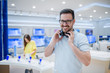 Happy man posing with earphones in tech store. Technology shopping concept.
