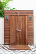 Outdoor Shower Made From Brown Wood Near Swimming Pool.
