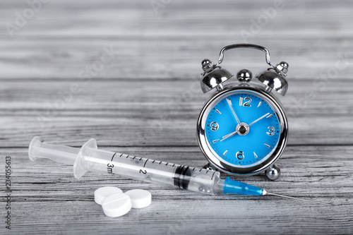 Fotografie, Obraz Time heals concept. Alarm clock with pills and syringe