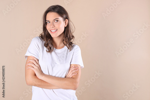 Fotomural Cheerful brunette woman dressed in basic clothing looking at camera, isolated on beige background