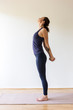 © Dante - young woman stands in blue yoga outfit stretching