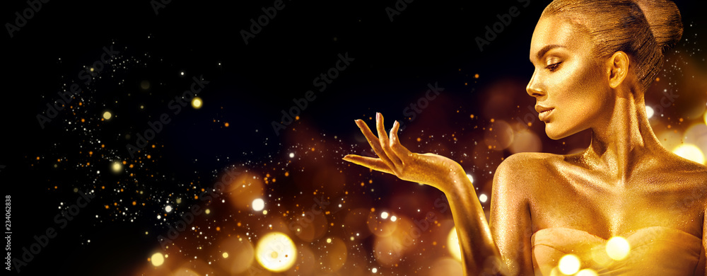 Gold Christmas woman. Beauty fashion model girl with golden makeup, hair and jewellery pointing hand on black background - obrazy, fototapety, plakaty 