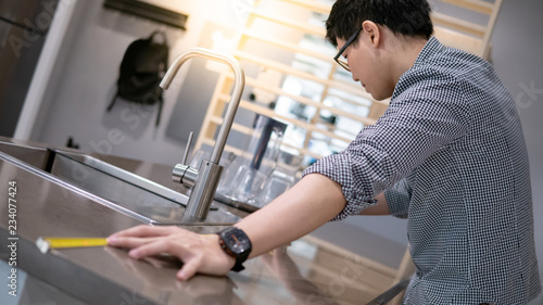 Young Asian Man Using Tape Measure For Measuring Granite