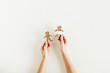 © Floral Deco - Female hands hold gingerbread man and woman cookies isolated on white background. Flat lay, top view Christmas / New Year food concept.