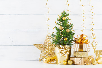 Winter composition with Christmas gift or present boxes, fir tree and golden holiday decorations on wooden background.