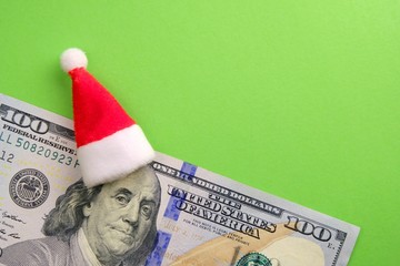 President Franklin with a Santa Claus hat on his head. US hundred dollar bill on a green background. The concept of New Year holidays and financial spending. Copy space.