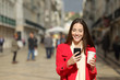 © Antonioguillem - Front view of a happy woman using phone in winter