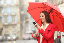 Happy Woman In Red Using A Phone Under The Rain