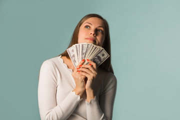 beautiful young girl considers dollars on blue background