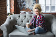 © BestForYou - Smiling beautiful woman on sofa with laptop and coffee.