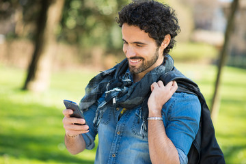 Wall Mural - Portrait of a man using his mobile phone in a park