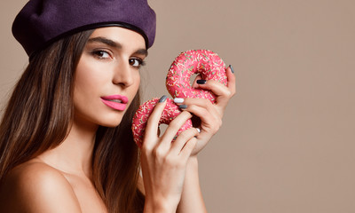 Wall Mural - Woman eat sweet pink sugar donuts hungry mouth on light brown background