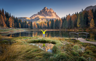 Wall Mural - man with raised up arms on antorno lake with reflection of tre cime di lavaredo at sunrise in autumn