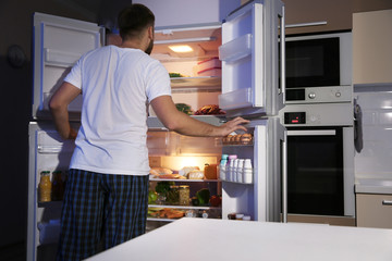 Sticker - Young man looking for food in refrigerator at night