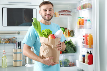 Sticker - Man with bag of products standing near refrigerator in kitchen