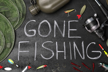 Flat Lay Composition With Angling Equipment And Words "GONE FISHING" On Dark Background