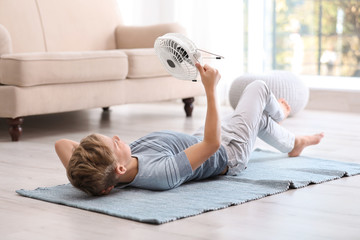 Canvas Print - Little boy with fan relaxing at home. Summer heat