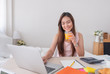 © weedezign - Asian female freelancer drink orange juice and and working on laptop at home.Work at home concept.work from home concept.