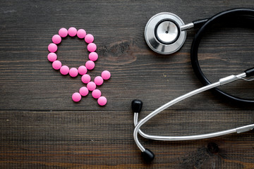 Female diseases concept. Stethoscope near female sign on dark wooden background top view copy space