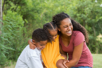 Wall Mural - Brother and sisters playing and laughing in a field.