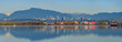 Panoramic view of cargoes at dock with colourful reflection on the river and city skyline and mountains at background at Richmond, BC