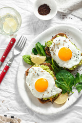 Wall Mural - Top view healthy avocado toasts breakfast lunch fried eggs white background lemon water