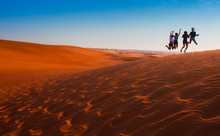 Happy People Jumping In The Desert Sunset Landscape. Travel Concept