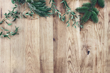 Christmas background. Border, frame of green fir, eucalyptus and pine tree branches on old wooden oak table. Winter festive banner. Vintage look. Flat lay, top view.