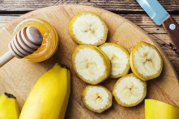 Banana and sliced banana into pieces with honey on wooden background, close-up