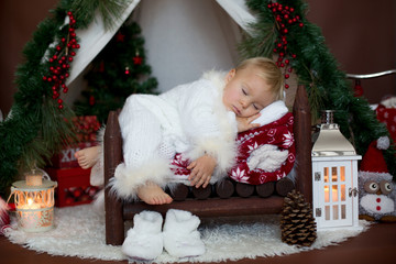 Canvas Print - Adorable little toddler baby boy dressed in canta claus costume, sleeping in baby bed in front of Christmas teepee