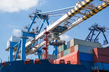 Container ship in port at container terminal close-up. Ships of container ships stand in terminal of port on loading, unloading container.