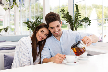 Sticker - Smiling young couple sitting at the cafe table