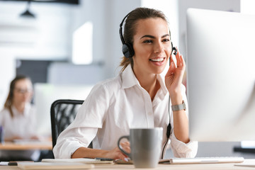 emotional business woman in office callcenter working with computer wearing headphones.