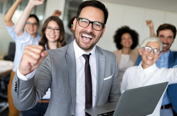 Happy business people celebrating success at company.