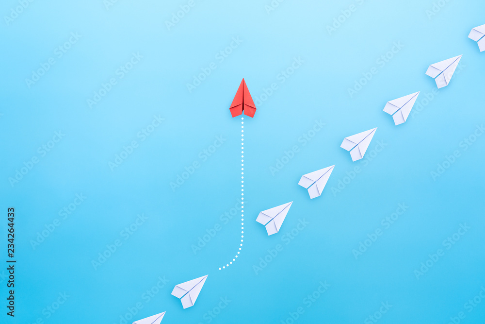 Business concept for innovation and solution with group of white paper plane in one direction and one red paper plane pointing in different way on blue background. - obrazy, fototapety, plakaty 