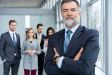 Businessteam In Office, Happy Senior Businessman In His Office Is Standing In Front Of Their Team.