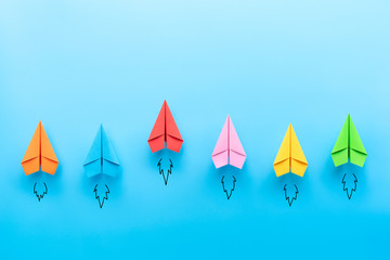 Wall Mural - Multicolored paper planes on blue background, Business competition concept with copy space