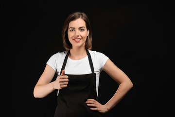 Young female chef on dark background