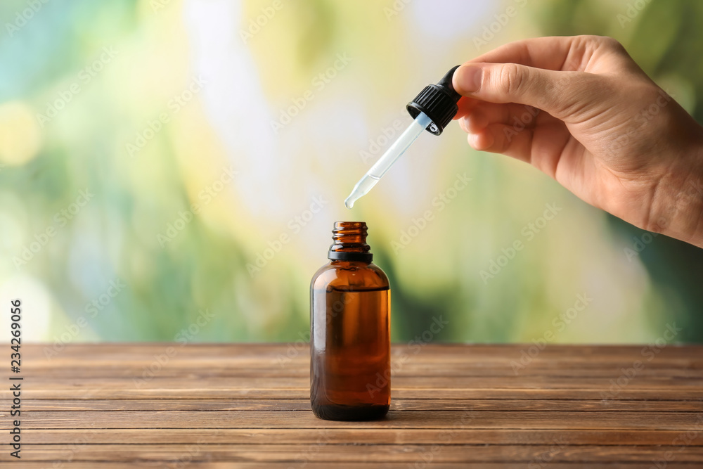 Female hand and bottle with eucalyptus essential oil on blurred background
