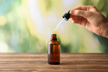 Female Hand And Bottle With Eucalyptus Essential Oil On Blurred Background