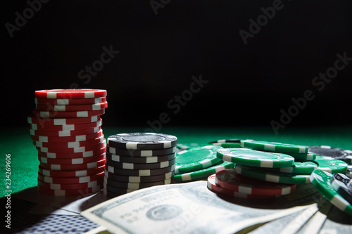 Foto A stack of gambling chips, cards one hundred dollar bills on green table