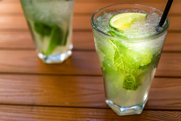 Two glasses of mojito cocktail with lime and mint on wooden table