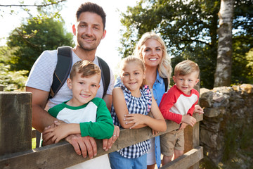 Family Hiking In Lake District UK Looking Over Wooden Gate