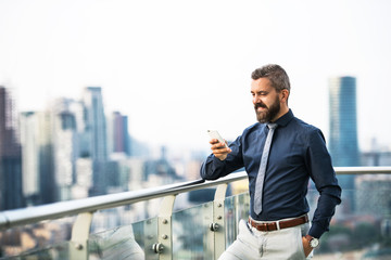 Poster - A portrait of businessman with smartphone standing against London view panorama.