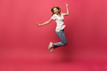 Happiness, Freedom, Motion And People Concept - Smiling Young Woman Jumping In Air Over Pink Background