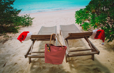 Wall Mural - Christmas on beach -chair lounges with Santa hats at sea