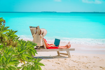 Wall Mural - remote work concept -young woman with laptop on beach