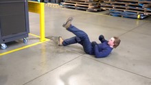 A Young Male Worker Slipping On A Wet Floor In A Factory.  An Industrial Safety Topic.